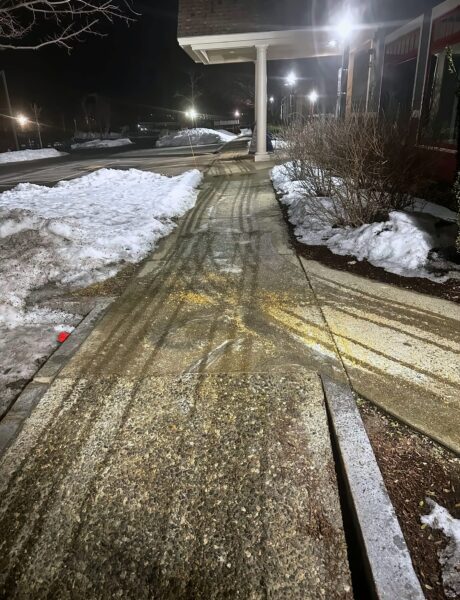 Brine lines and treated salt on a commercial walkway at night in southern NH by NorthShire